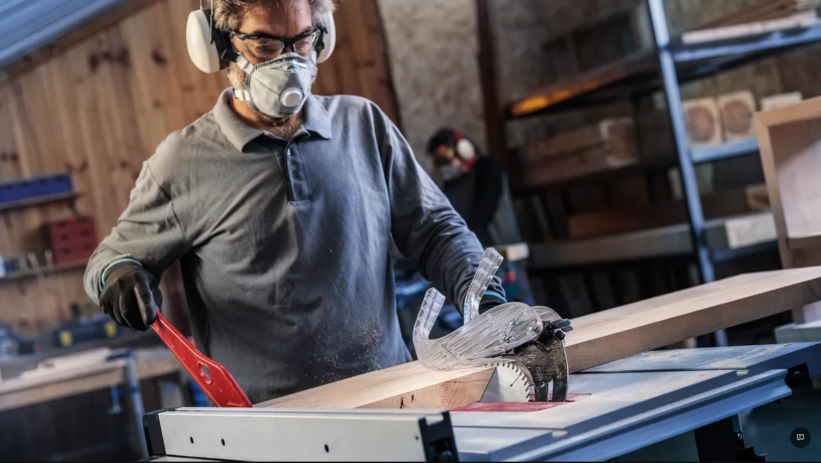 Worker feeding a board through a table saw