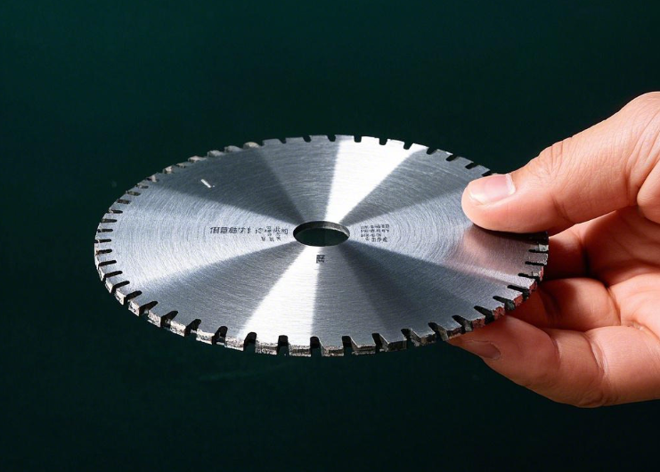 Hand holding a silver toothed circular saw blade